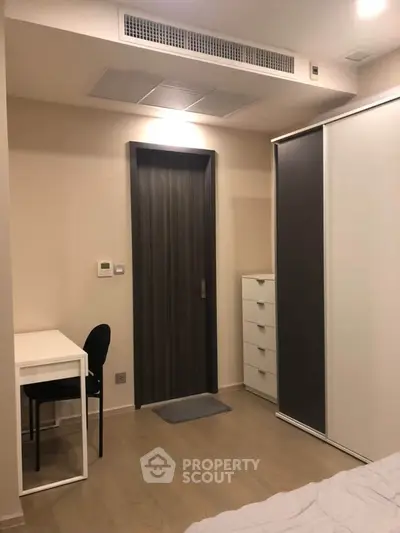 Modern bedroom with sleek furniture and neutral tones, featuring a study desk and ample storage space.