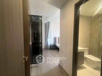 Modern apartment interior with bedroom and bathroom view, featuring sleek design and neutral tones.