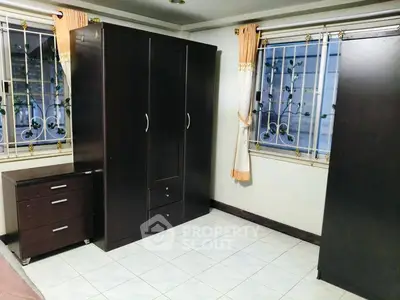 Spacious bedroom with elegant dark wood furniture and large windows with decorative grills.