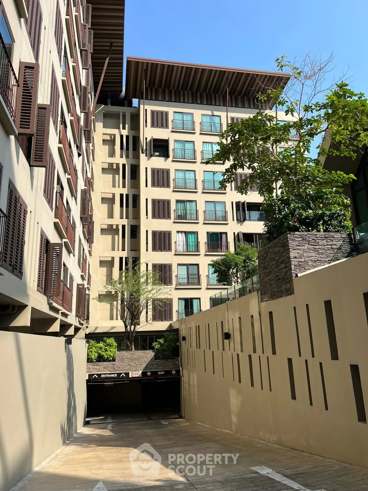 Modern apartment building exterior with parking entrance and lush greenery