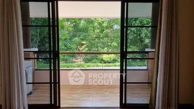 Spacious balcony with lush green view through sliding glass doors, perfect for relaxation.