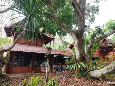 Charming rustic wooden house surrounded by lush greenery and mature trees, offering a serene natural retreat.