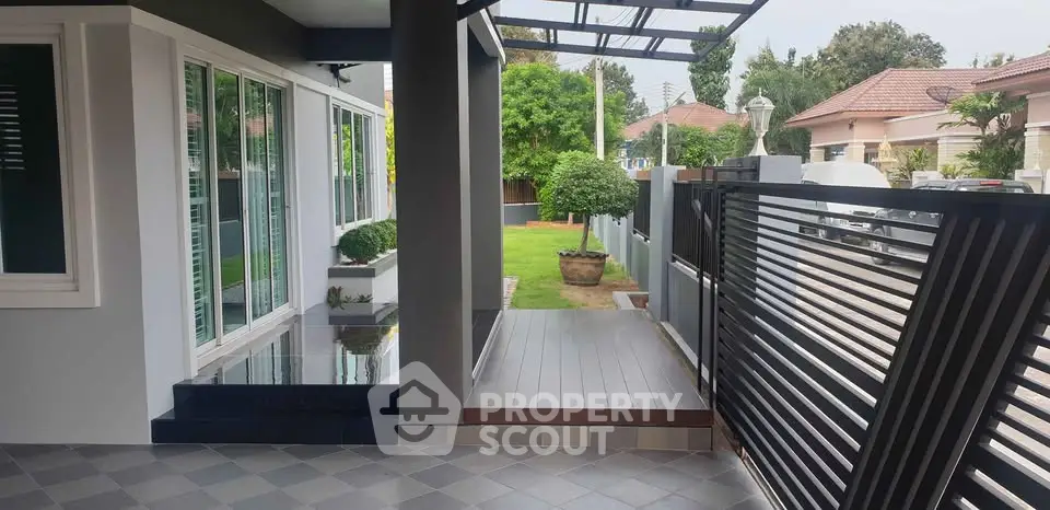 Modern home exterior with sleek design and lush garden view, featuring stylish entrance and contemporary fencing.