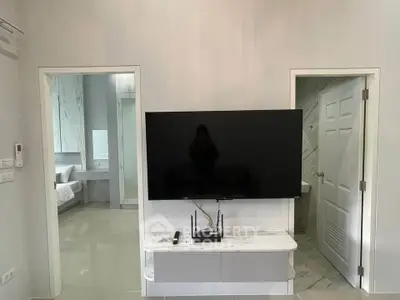 Modern living room with sleek TV setup and view into bedroom and bathroom.