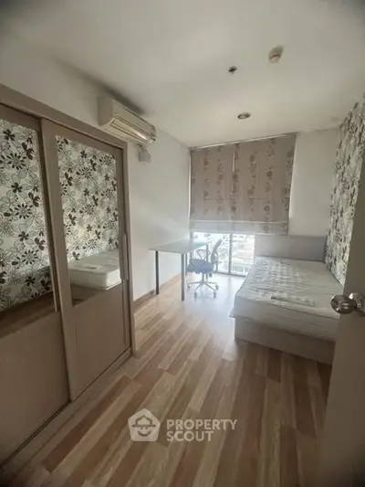 Cozy bedroom with floral wallpaper, wooden flooring, and natural light