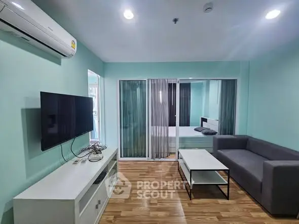 Modern living room with sleek furniture and glass partition leading to bedroom