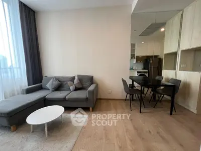 Modern living room with cozy gray sofa and dining area in open layout apartment.