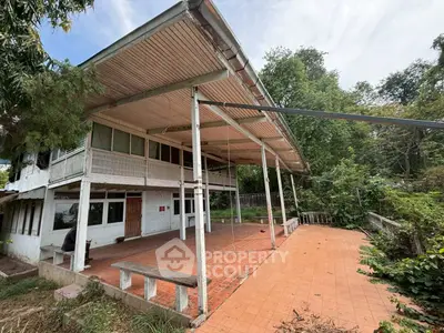 Spacious outdoor terrace of a rustic property surrounded by lush greenery.