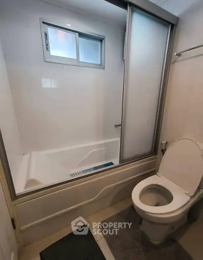 Modern bathroom with sleek bathtub and toilet in a compact space.