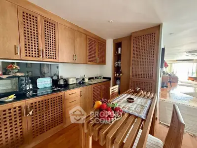 Charming kitchen with wooden cabinetry and dining area in cozy apartment
