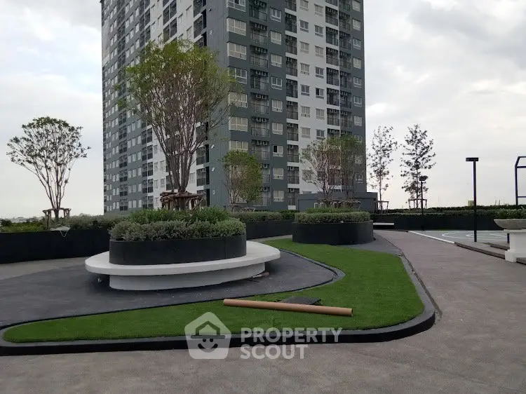 Modern high-rise building with landscaped garden and outdoor seating area.