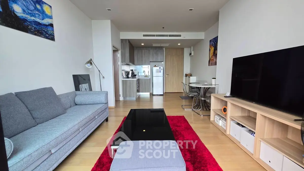 Modern living room with open kitchen, stylish decor, and vibrant red rug