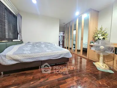 Spacious bedroom with wooden flooring and large wardrobe