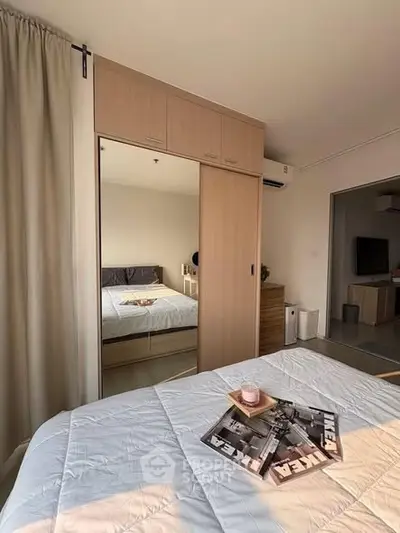 Modern bedroom with mirrored wardrobe and cozy decor in a sunlit apartment.