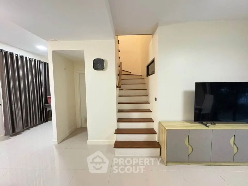 Modern interior with sleek staircase and stylish TV console in a spacious living area.