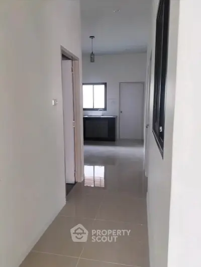 Spacious hallway leading to a modern kitchen with sleek tile flooring and ample natural light.