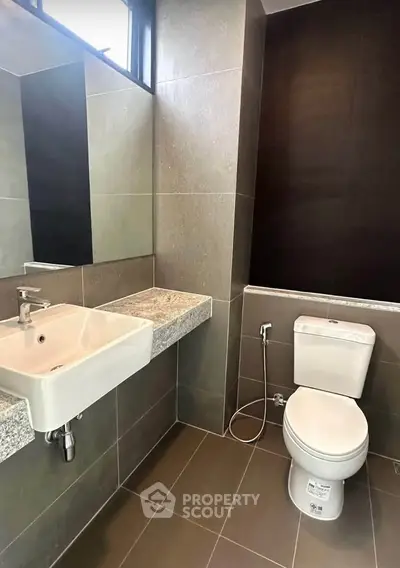 Modern bathroom with sleek design featuring a wall-mounted sink and toilet.