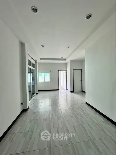 Spacious modern living room with sleek tile flooring and recessed lighting, perfect for contemporary living.