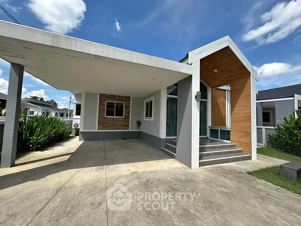 Modern single-story house with carport and stylish facade under a bright blue sky.