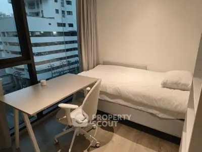 Modern bedroom with city view, featuring a cozy bed and sleek desk setup.