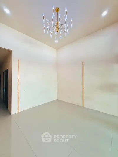Spacious room with elegant chandelier and high ceiling, perfect for modern living.
