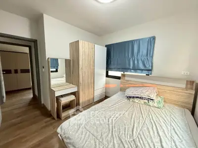 Modern bedroom with wooden furniture and blue curtains, featuring a cozy bed and ample storage space.