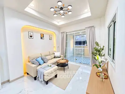Modern living room with stylish lighting and cozy seating area, opening to a spacious balcony.
