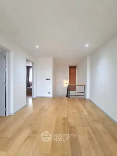 Spacious modern interior with wooden flooring and bright natural light, ideal for versatile living space.