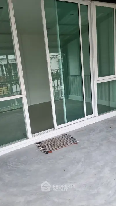 Spacious balcony with sliding glass doors and concrete flooring.