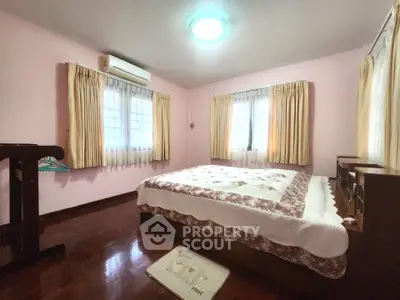 Cozy bedroom with wooden flooring and ample natural light from large windows.