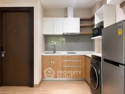 Modern compact kitchen with wooden cabinets, stainless steel fridge, and washing machine in a cozy apartment.