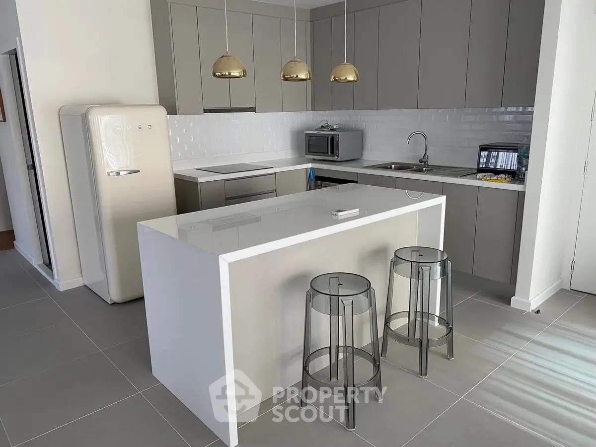 Modern kitchen with sleek cabinetry and island seating in a contemporary apartment.