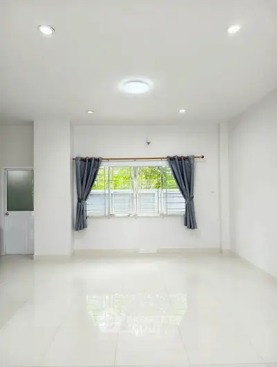 Spacious and bright living room with large windows and elegant curtains, perfect for modern living.