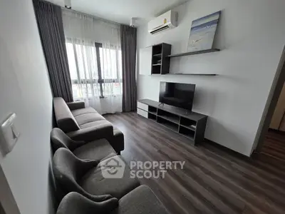 Modern living room with sleek furniture and large window offering natural light