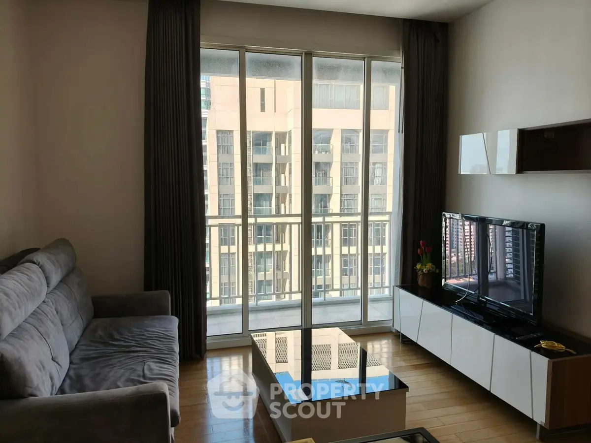 Modern living room with large windows and city view, featuring a cozy sofa and sleek TV unit.
