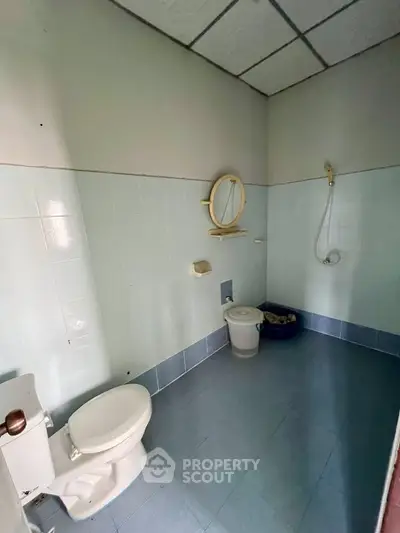 Spacious bathroom with blue tiles and basic fixtures, ideal for renovation.