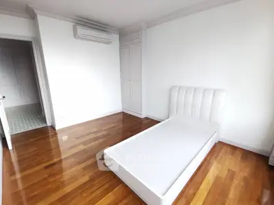 Spacious bedroom with wooden flooring and modern air conditioning unit