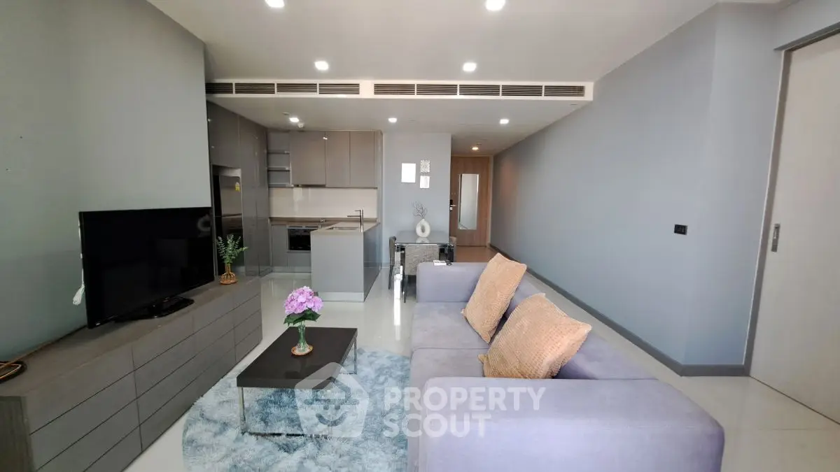 Modern living room with sleek furniture and open kitchen layout in a stylish apartment.