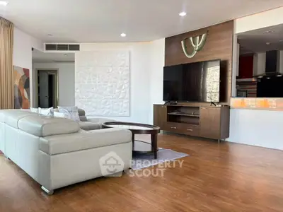 Spacious modern living room with sleek furniture and large TV, perfect for relaxation and entertainment.