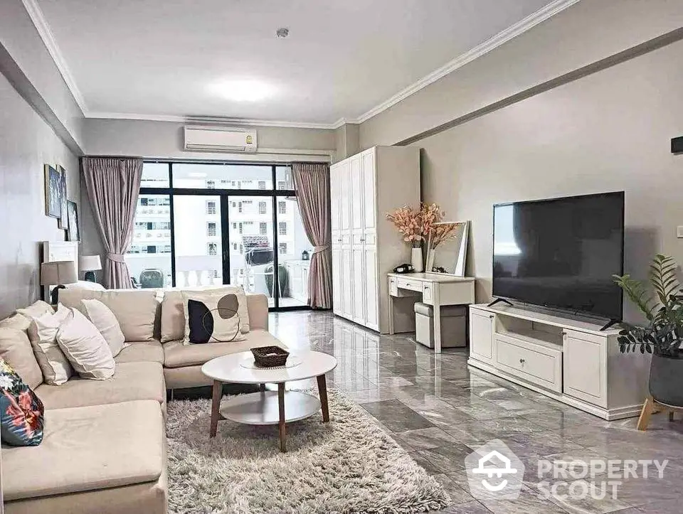 Spacious modern living room with elegant decor and large TV, perfect for relaxation.