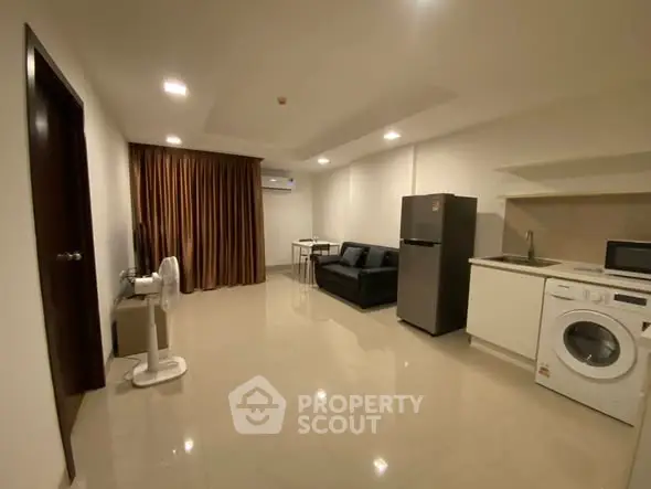 Modern studio apartment with open layout, featuring kitchen appliances and cozy living area.