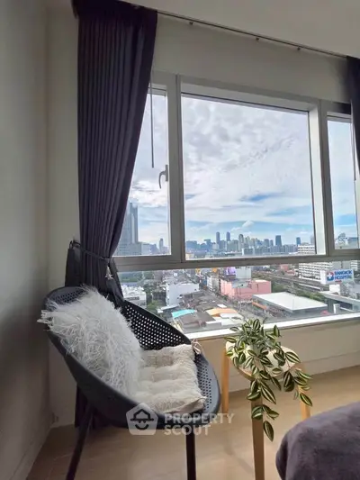 Stylish apartment with stunning city view from large window, cozy seating area with modern decor.