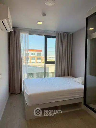 Modern bedroom with large window and minimalist design in urban apartment.