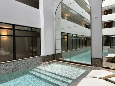 Luxurious indoor pool area with modern design and elegant lounge chairs in a high-end residential building.
