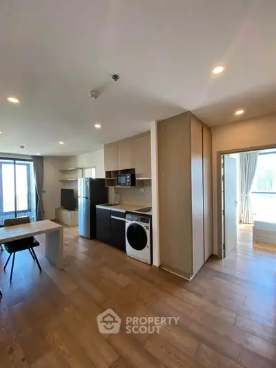 Modern open-plan kitchen and living area with wooden flooring and natural light.