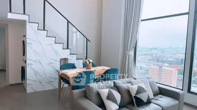 Modern living room with large windows and city view, featuring stylish furniture and elegant decor.