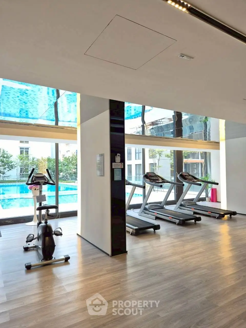 Modern gym with pool view and exercise equipment in luxury real estate property.
