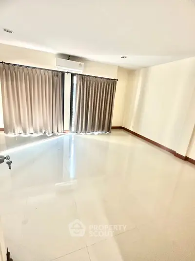 Spacious empty room with large windows and air conditioning, perfect for customization.