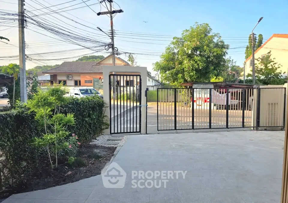Spacious residential driveway with secure gate and lush greenery in a serene neighborhood.