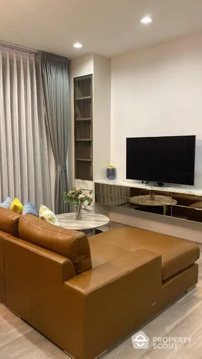 Modern living room with leather sofa and large TV, perfect for relaxation and entertainment.